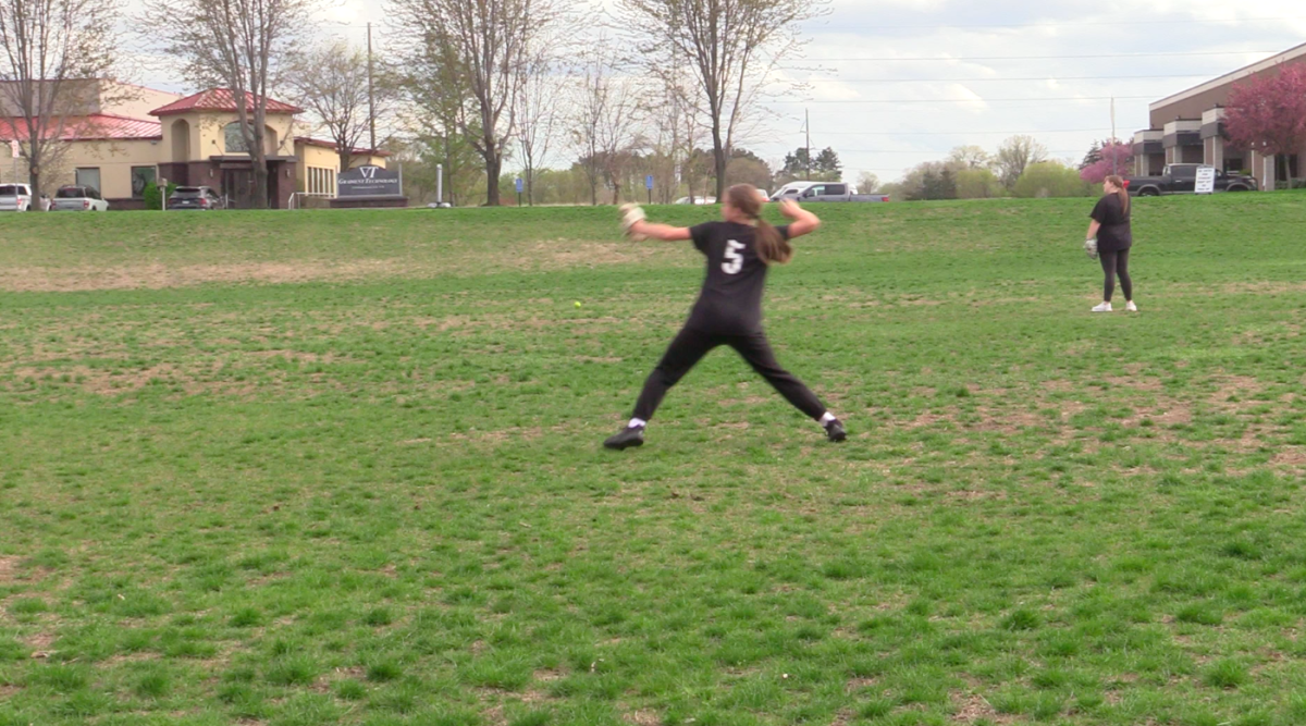 Ella Burquest throwing a ball during softball practice.