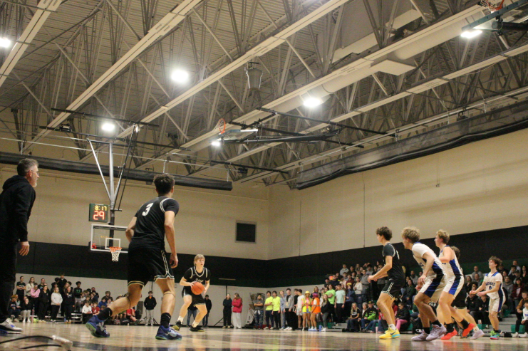 Senior Captain Eli Miller dribbling the ball during the Homecoming basketball game against North Lakes at the New Gym.